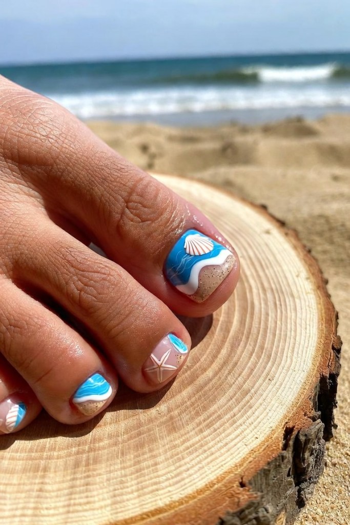 Beach-themed pedicure nail art with seashells and starfish